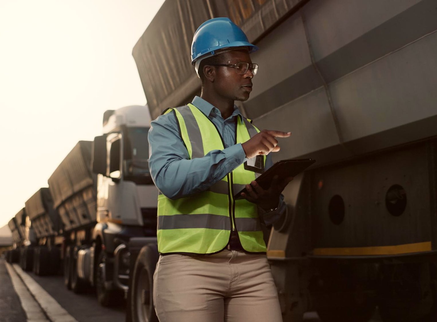 Supply chain professional inspecting mining trucks at golden hour